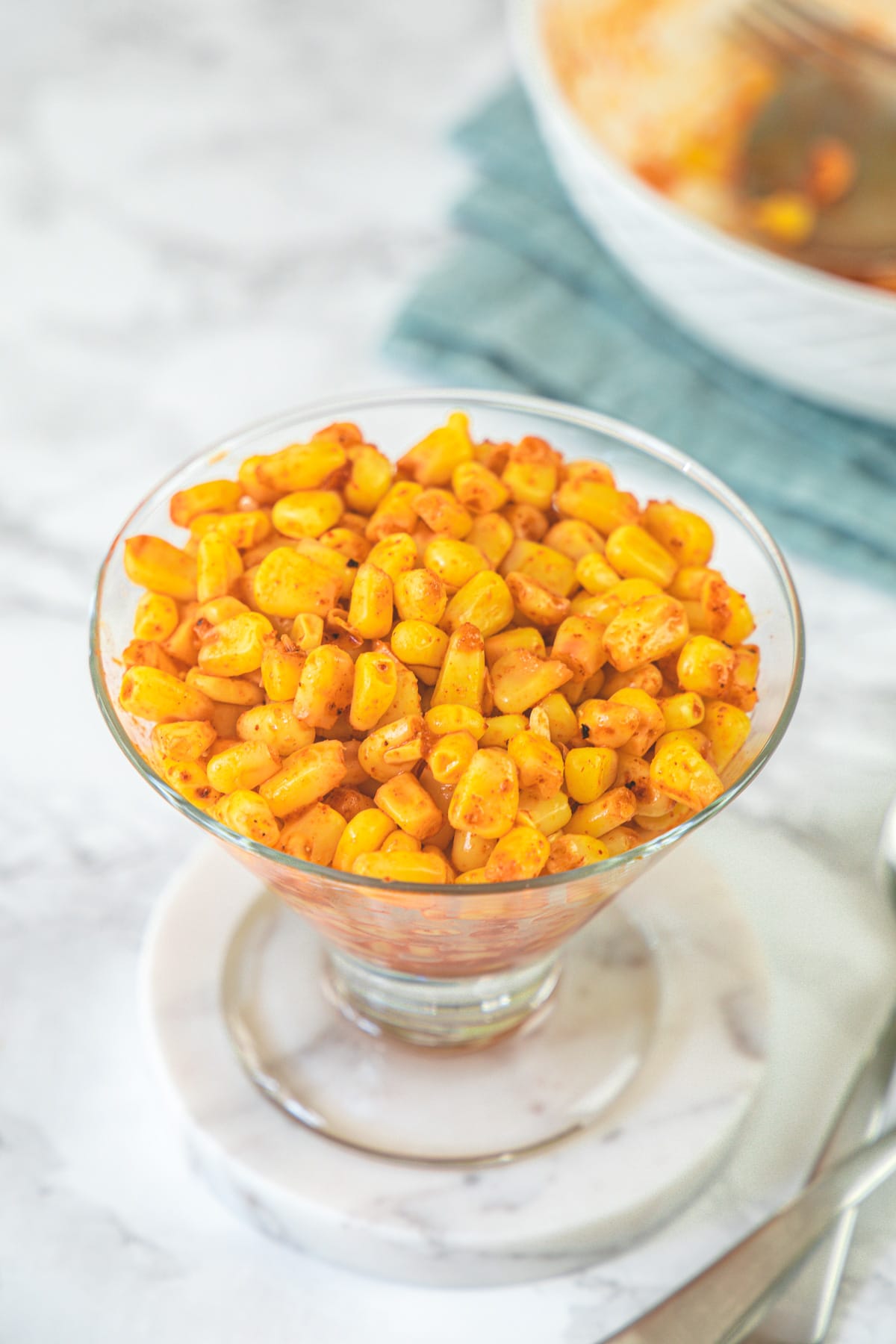 A bowl of masala corn with spoons on the side.