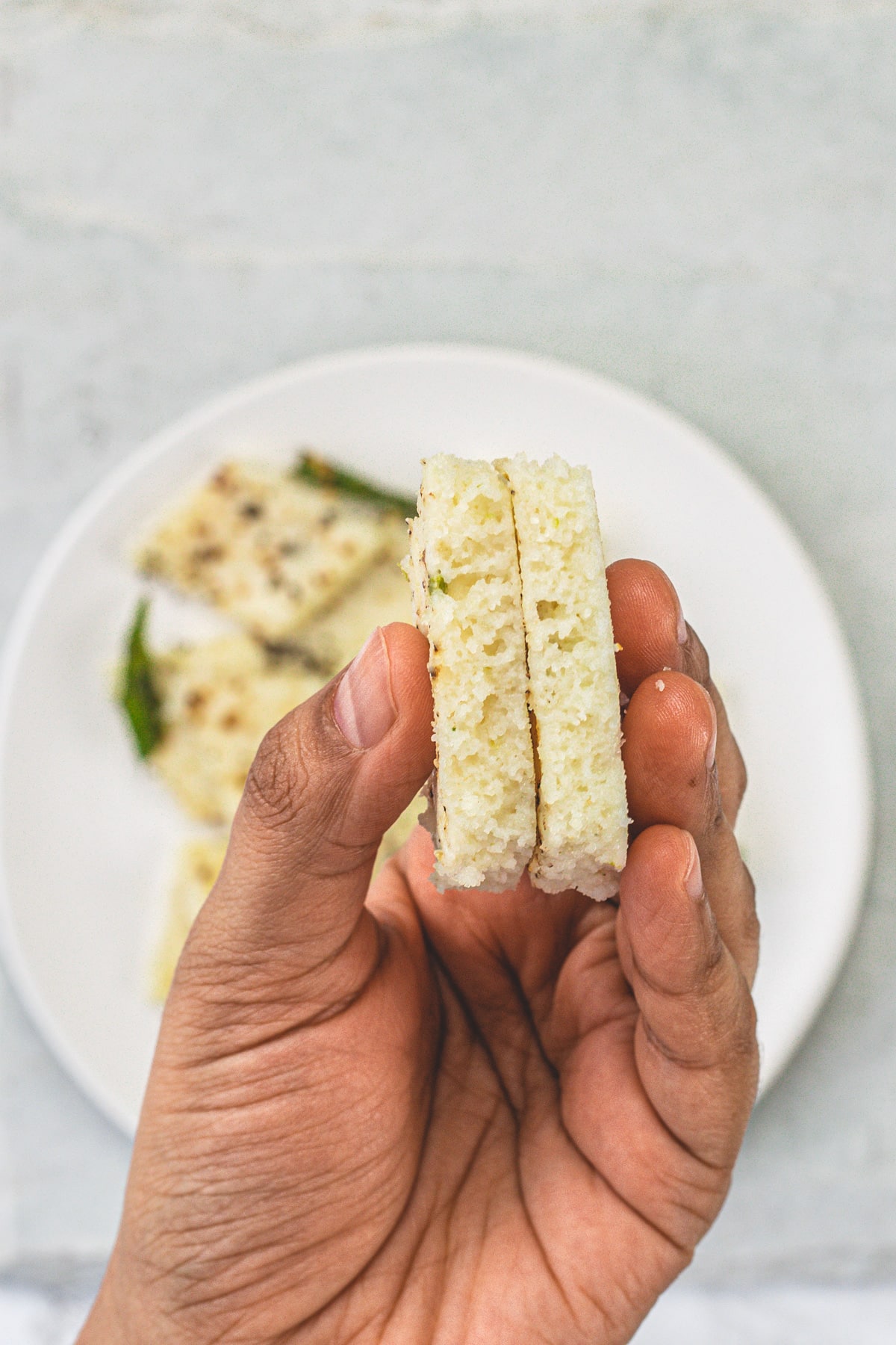 2 pieces of rava dhokla holding in a hand.
