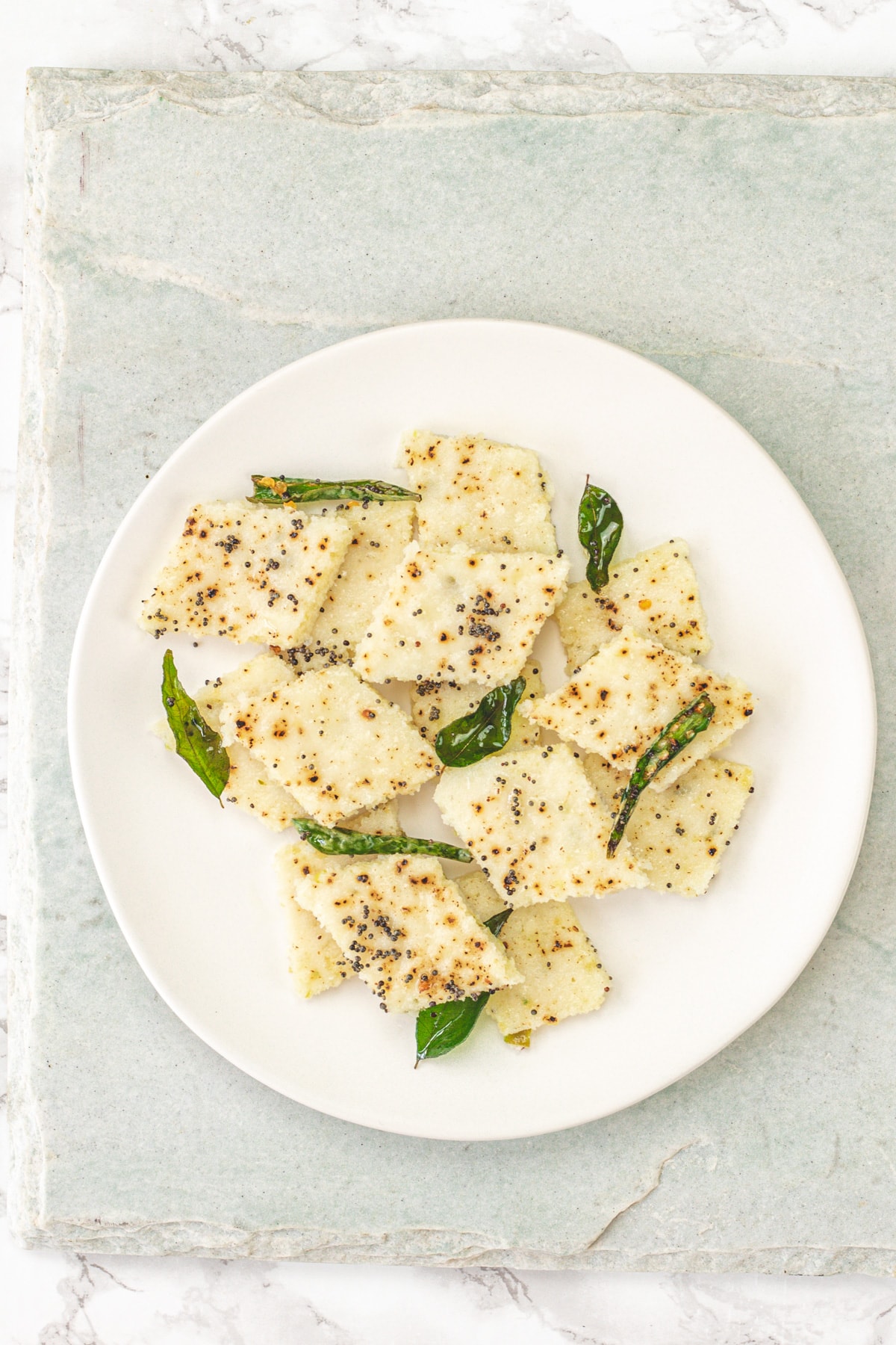 A plate of rava dhokla on a marble board.