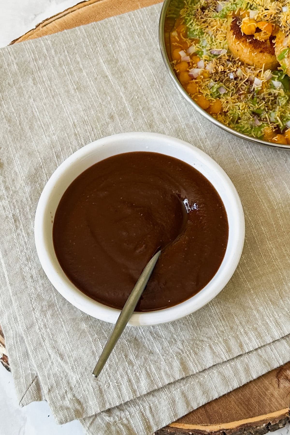 Tamarind date chutney in a bowl with a spoon in it.