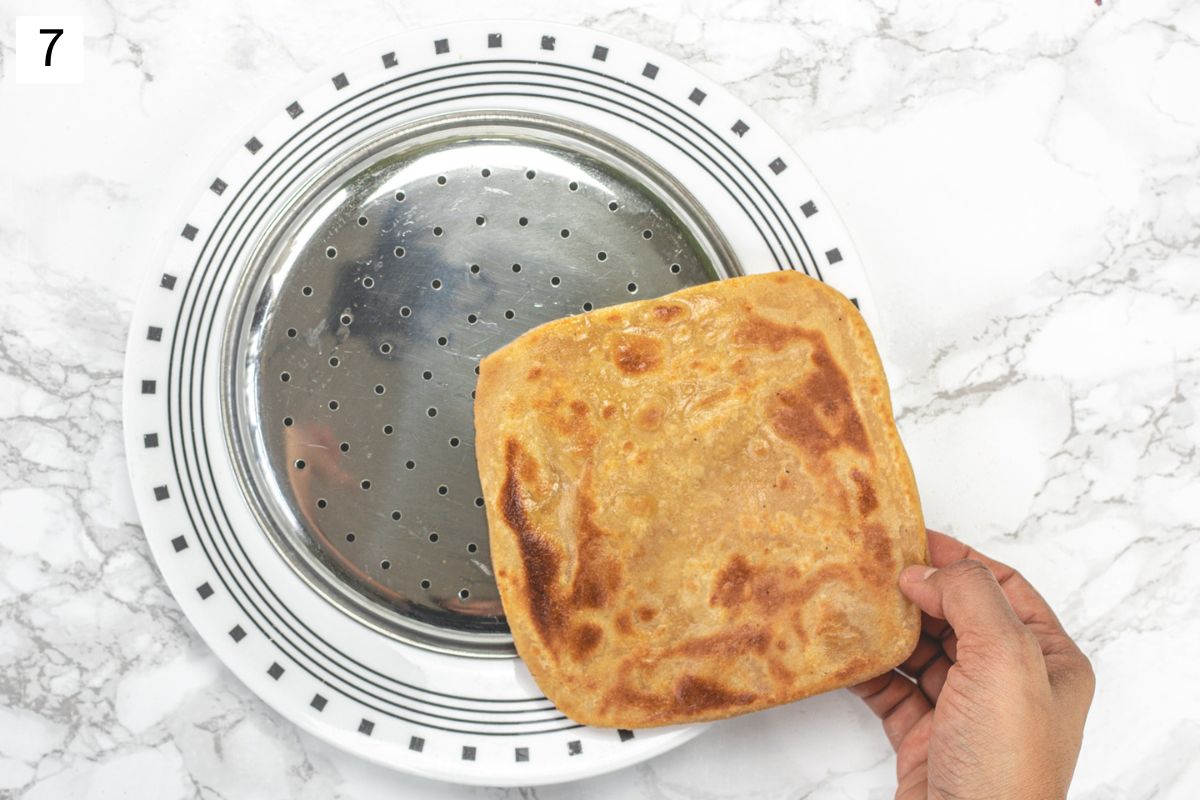 Square plain paratha placing on a perforated plate.