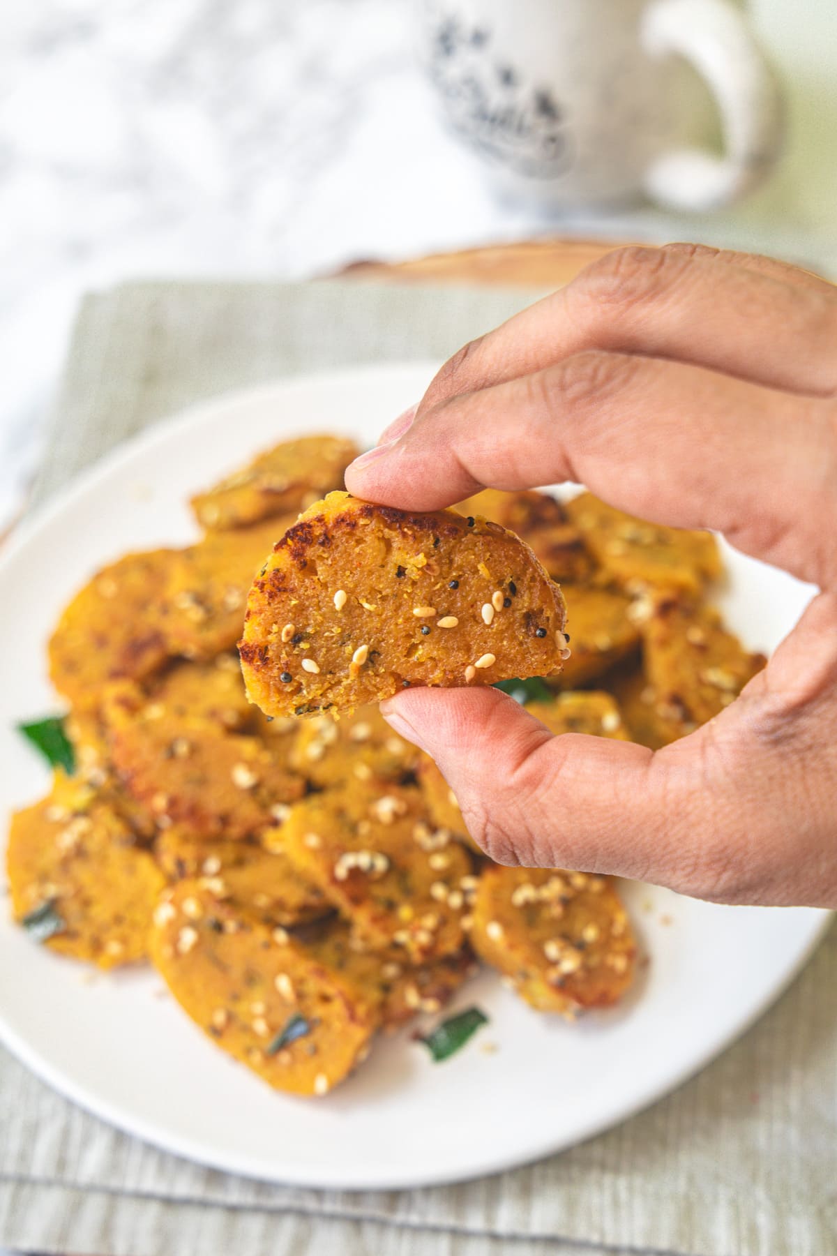 Taking one piece of muthia from the plate.