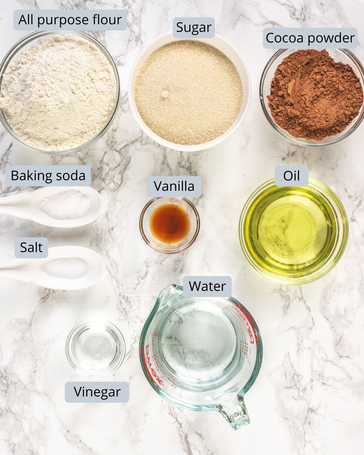 Eggless chocolate cupcake ingredients in bowls and spoons with labels.