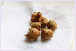 Deep fried methi gota in a paper towel lined plate.