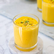 A glass of mango lassi garnished with saffron the pistachios.