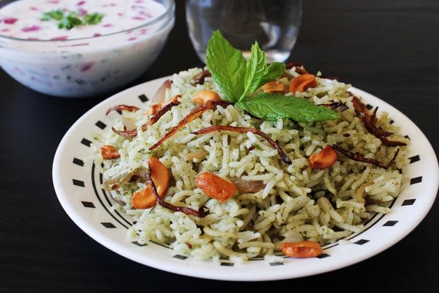 Mint rice in a bowl garnished with fried onion and cashews.