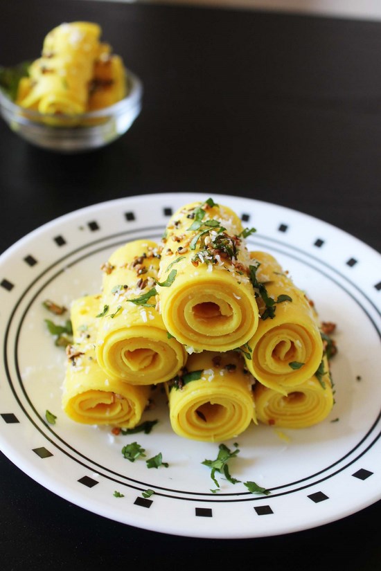 Khandvi stacked in a plate garnished with cilantro.