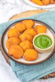 Aloo pakora in a plate with green chutney in a small bowl.