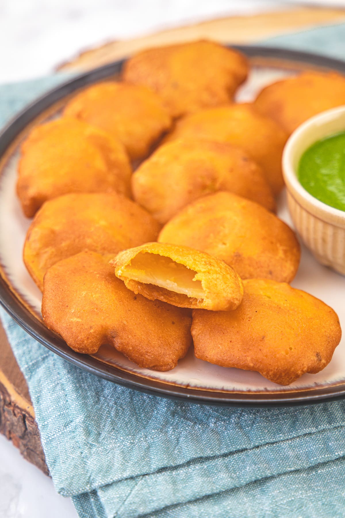 Aloo pakora in a plate with a bite taken from one pakora.