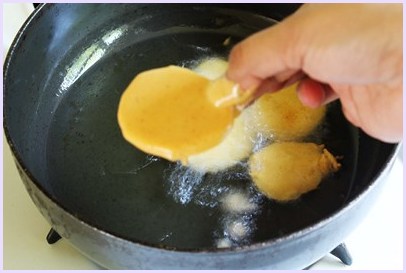 Batter coated potato sliced added into the oil.