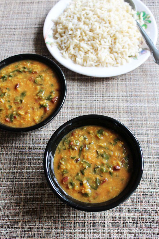 Beet greens dal in 2 bowls and a plate of brown rice in the back.