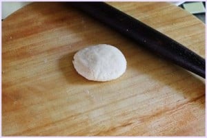 one flatten dough ball on the rolling board