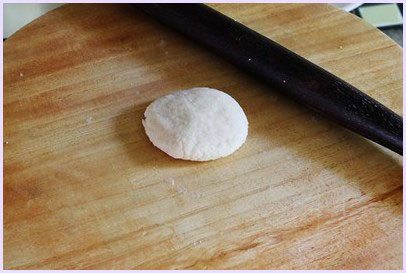 one flatten dough ball on the rolling board