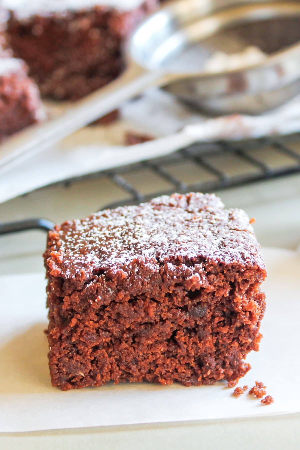 Egg free brownie on a parchment paper and more brownies in the back on a rack.