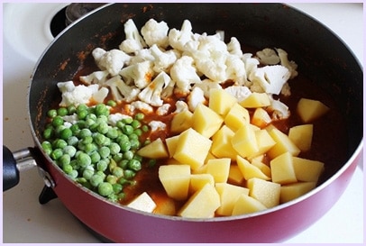 Adding potatoes, peas and cauliflower florets.