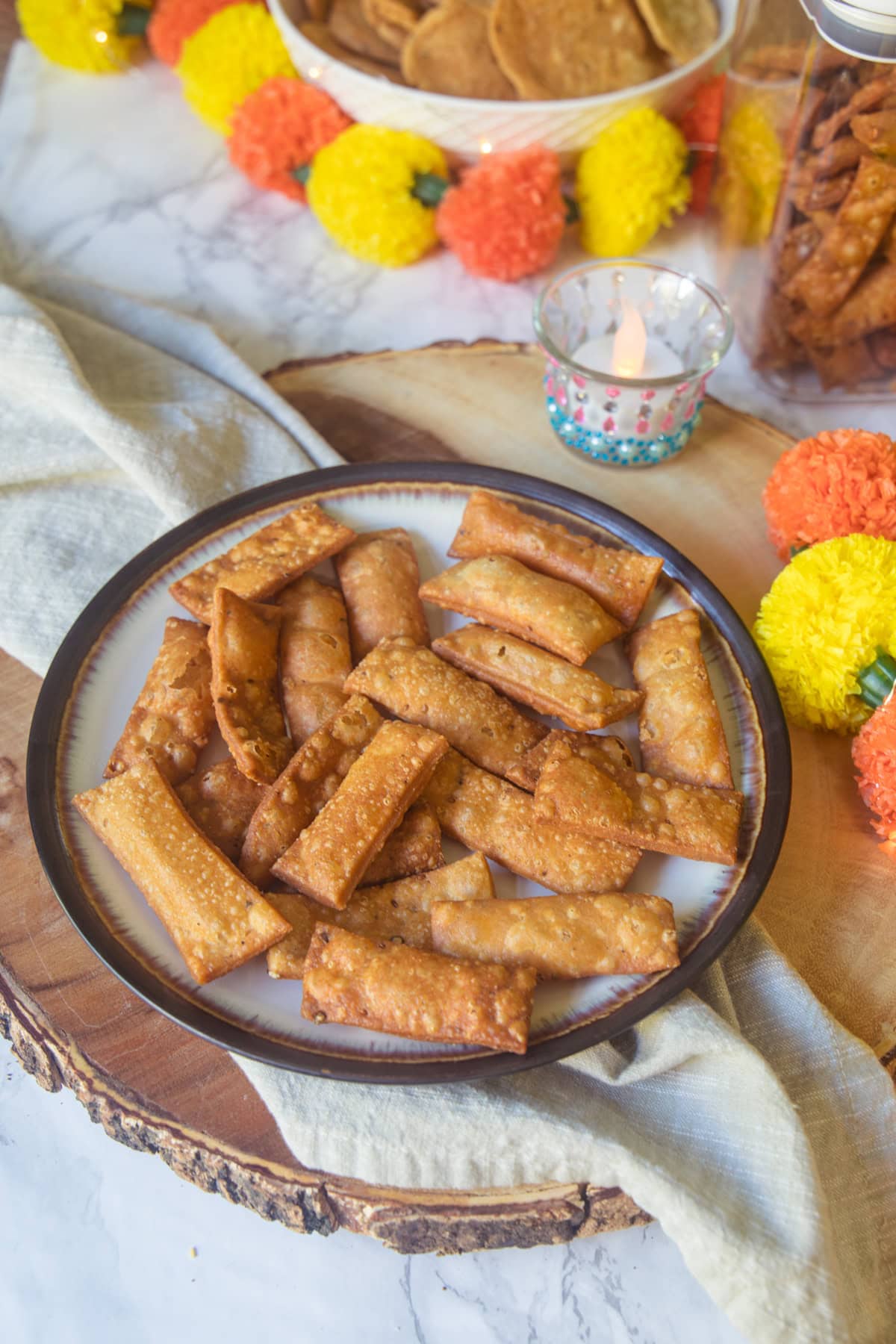 Namak para in a plate with diya and decor in the background.