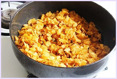 mixing corn flakes well to make namkeen