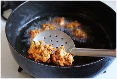 Removing pakora using slotted spoon.