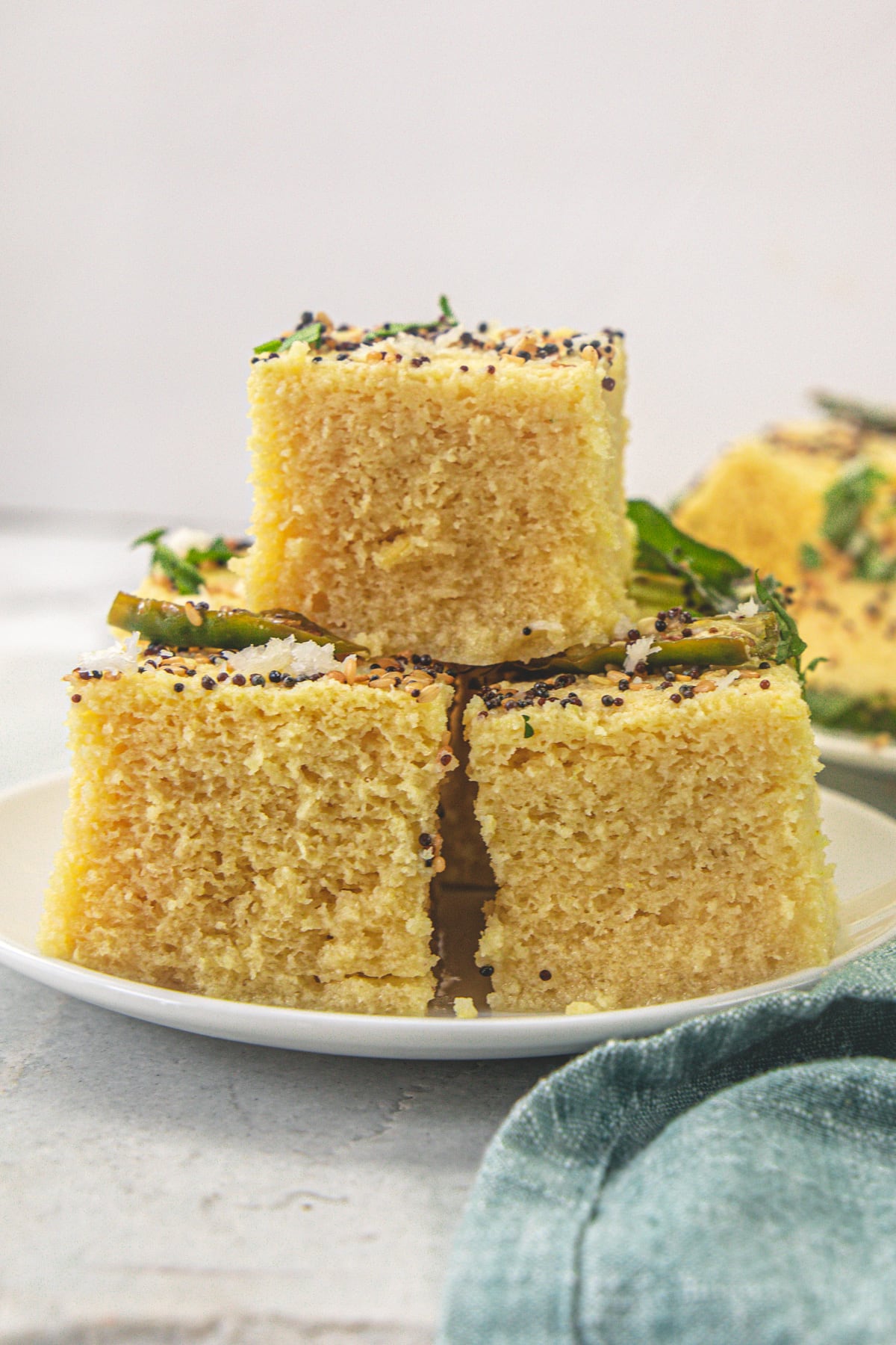 A stack of 3 khaman dhokla in a plate.