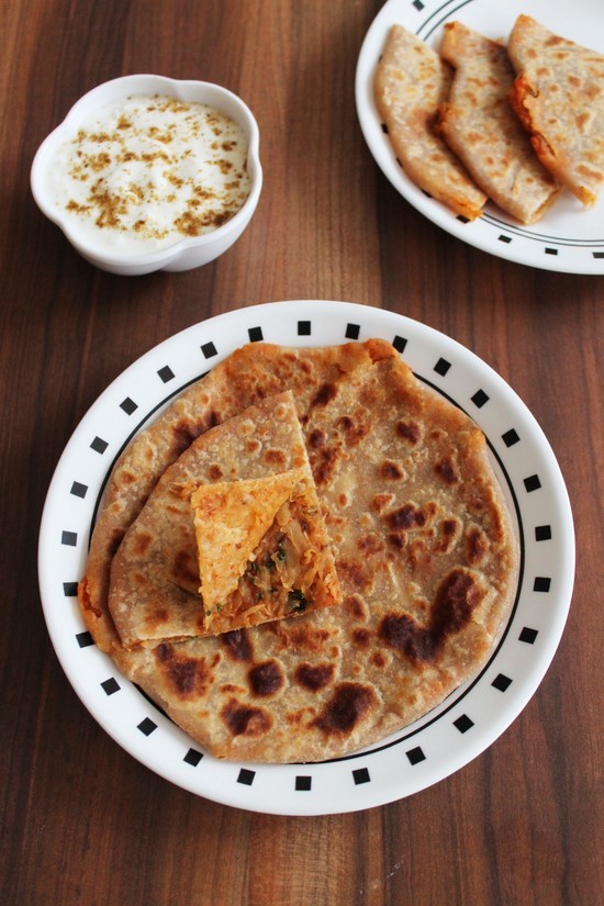 Mooli Paratha triangle is opened slightly with more paratha and yogurt in the back.