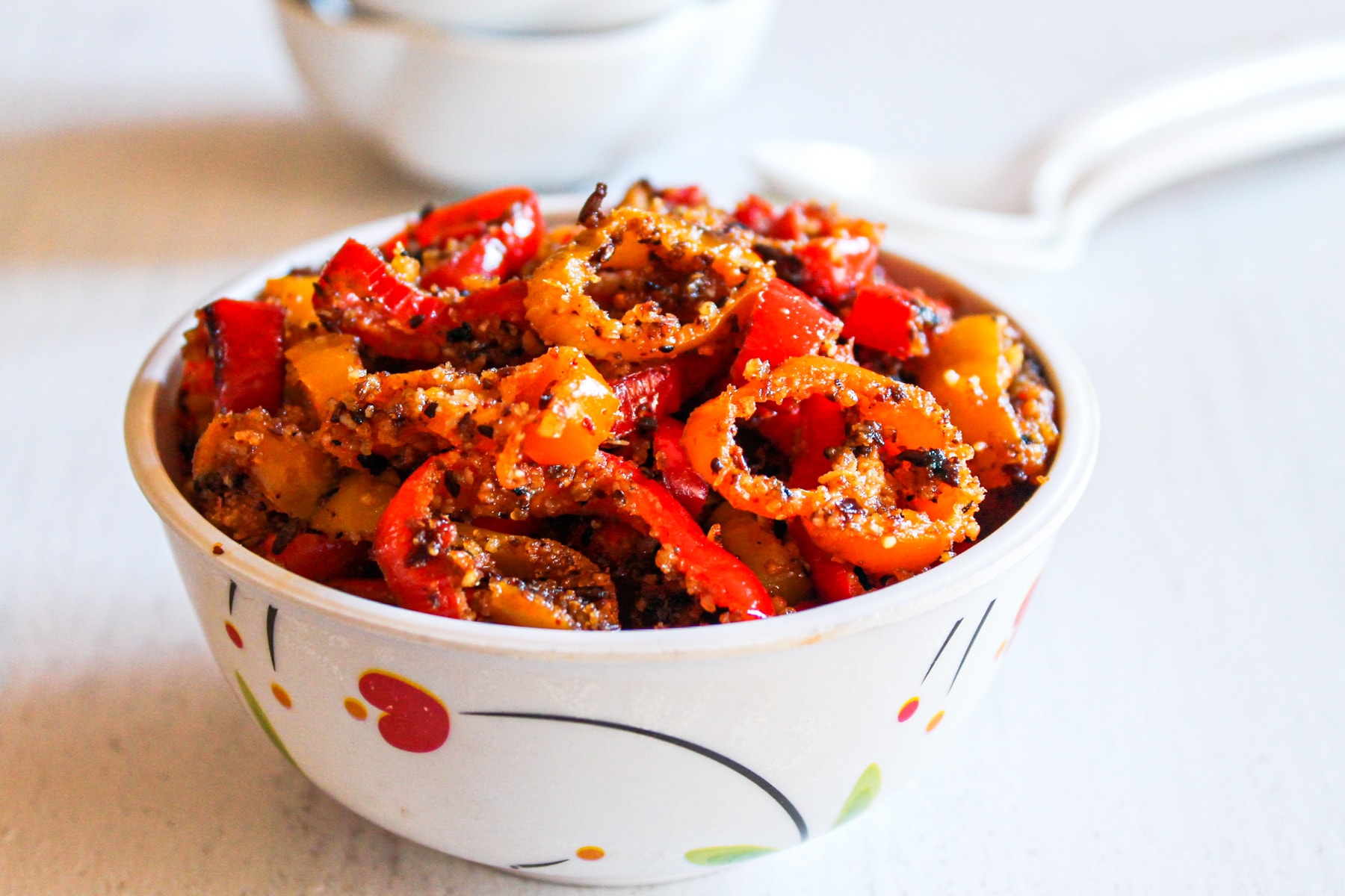 Mini sweet peppers sabzi served in a bowl with two spoons in the back.