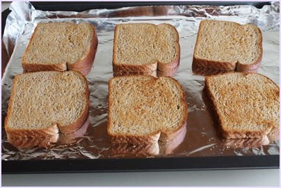 Toasted bread slices on aluminium foil lined tray.