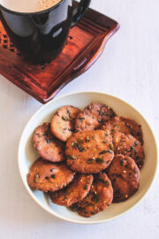 Bajri vada in a plate with a cup of tea in the back.