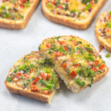 Slices of chilli cheese toast on a marble board.