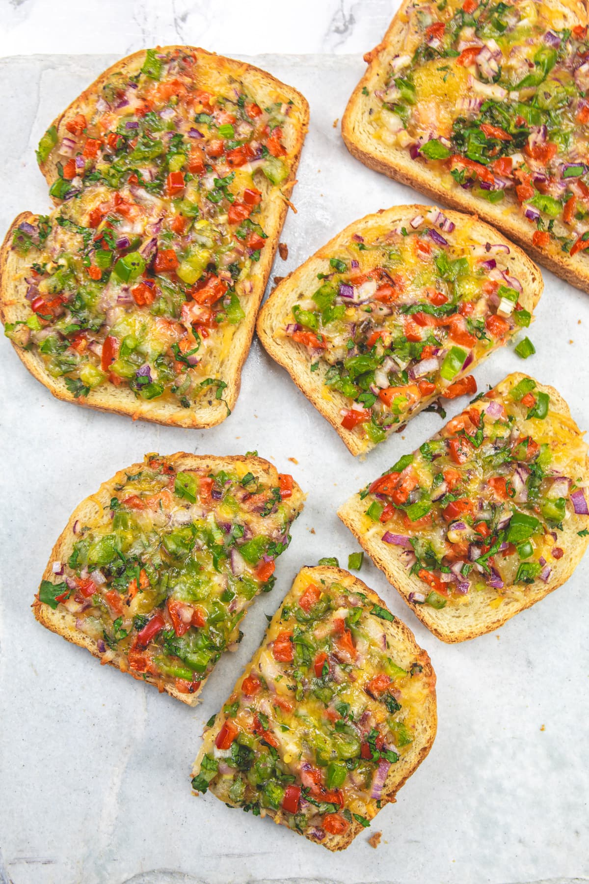 2 Chilli cheese toast cut into half and rest 2 with whole slices on a marble surface.