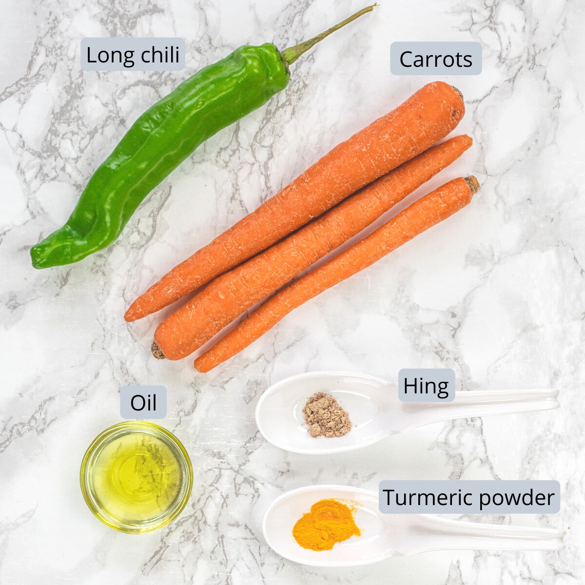 Carrot sambharo ingredients in spoons on marble surface with labels.