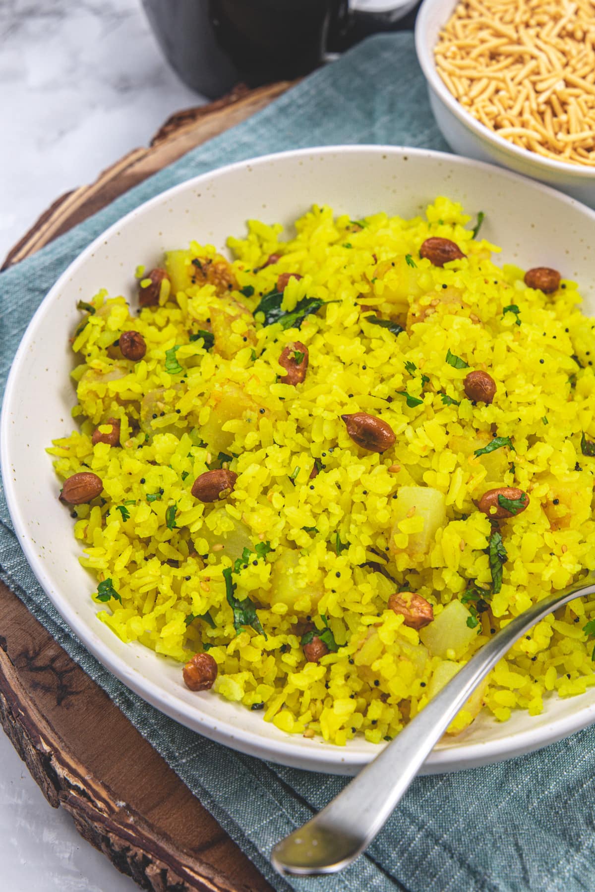 Poha served in a plate with a spoon.