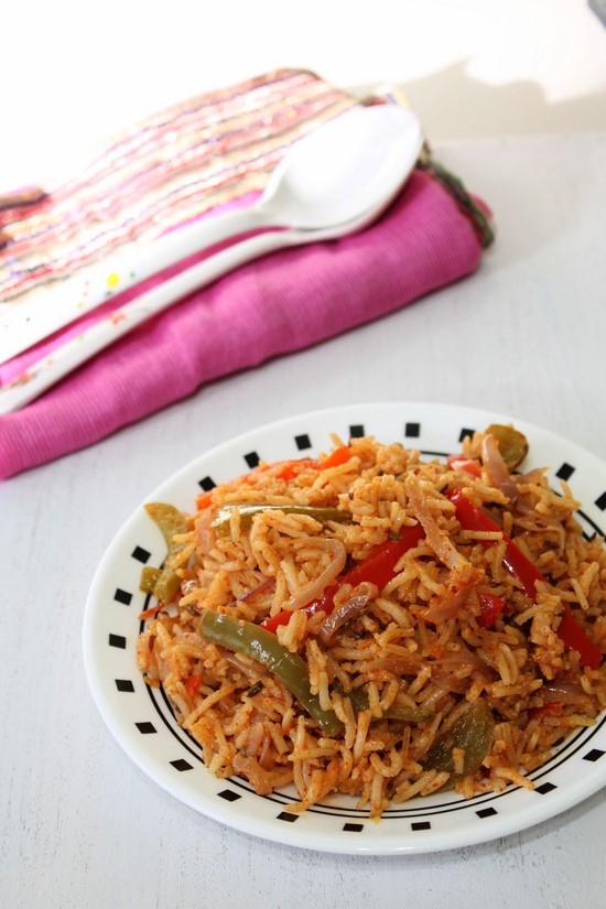 Capsicum Rice in a plate with spoons in the back.