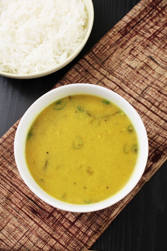 Amti served in a bowl with napkin under the bowl and rice plate in the back.