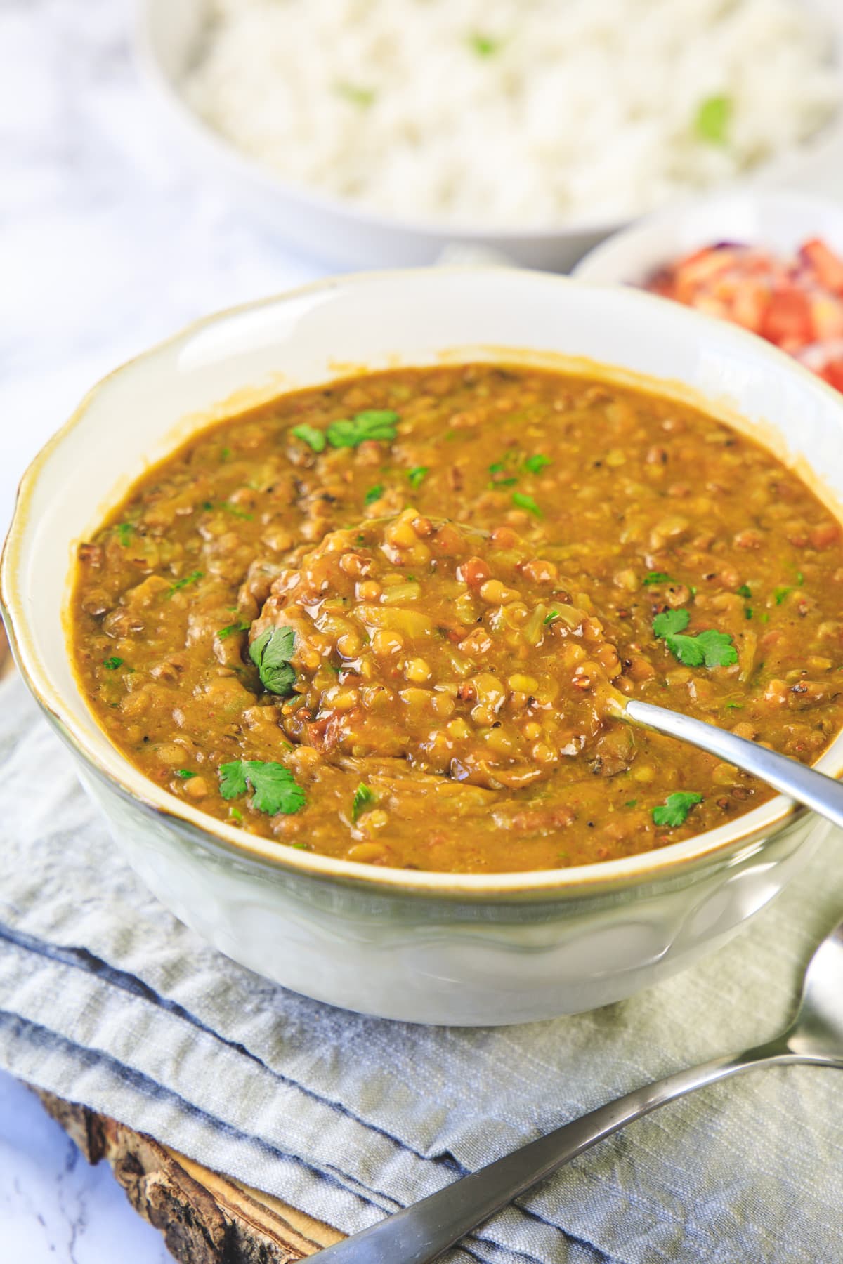 Taking spoonful of math dal from a bowl.