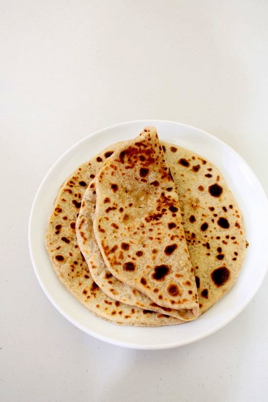 Gobi paratha in a plate and first paratha is folded in half.