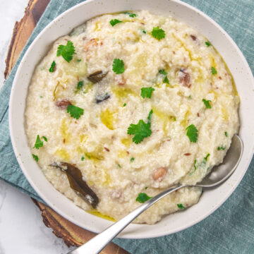 Moraiyo khichdi in a white plate with spoon, garnished with cilantro.