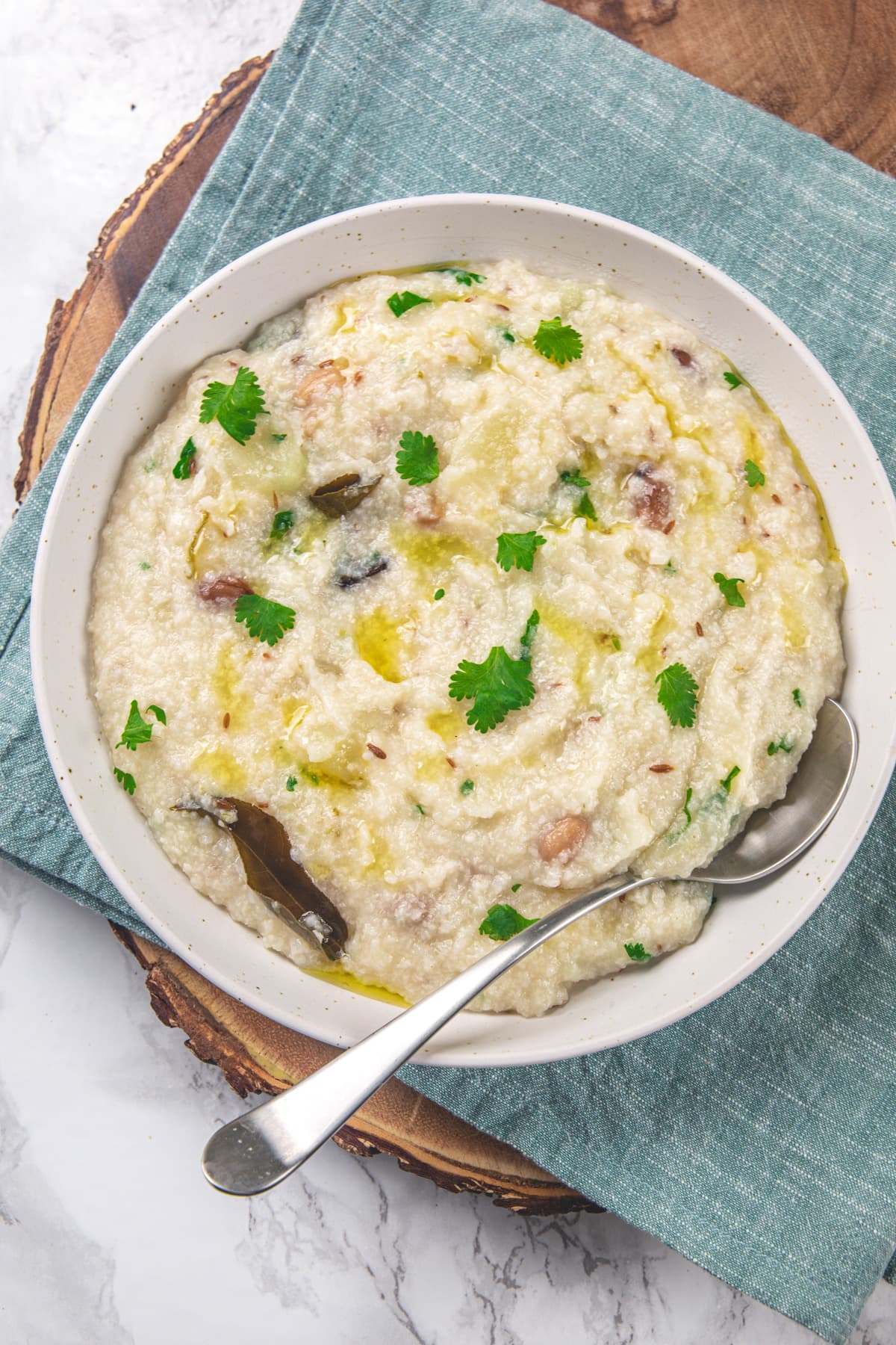 Moraiyo khichdi in a white plate with spoon, garnished with cilantro.