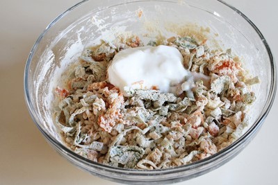 Adding yogurt to besan veggie mixture.