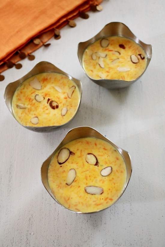 Carrot Kheer served in 3 steel bowls garnished with almond slices. 