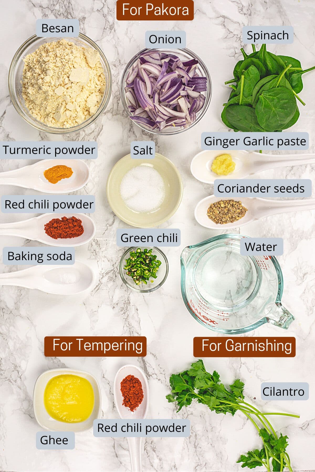 Pakora and tempering ingredients in bowls and spoons with labels.