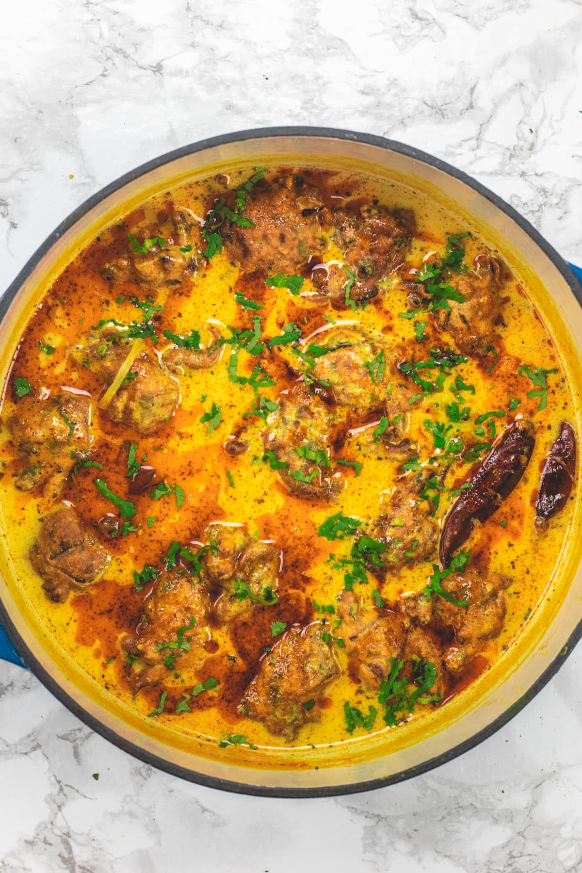 Punjabi kadhi pakora in a pan drizzled with tadka ghee and garnished with cilantro.