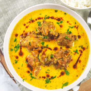 Punjabi kadhi pakora in a plate with a drizzle of ghee tadka and garnish of cilantro.