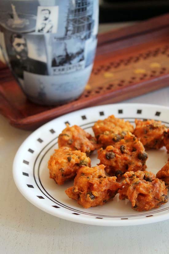 Rice Pakora in a plate with mug in a tray in the back.