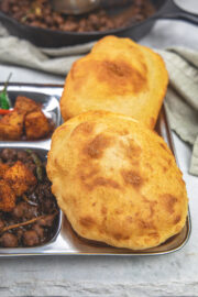 2 bhature in a plate with bhole and khatte aloo.