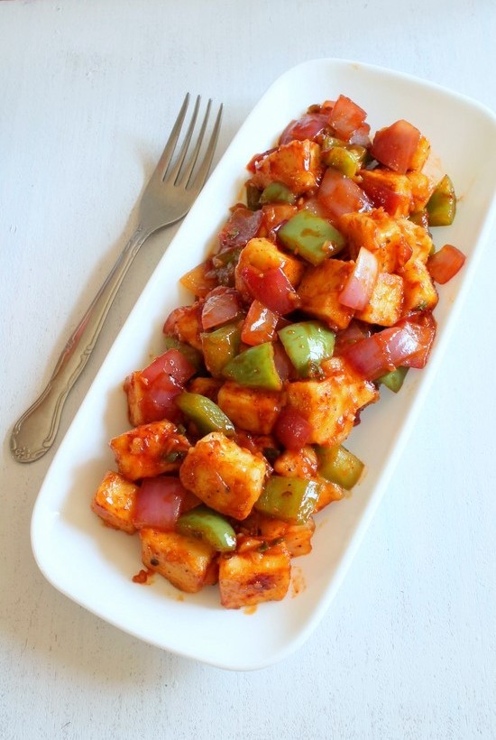 Chilli Paneer Dry in a plate with a fork.