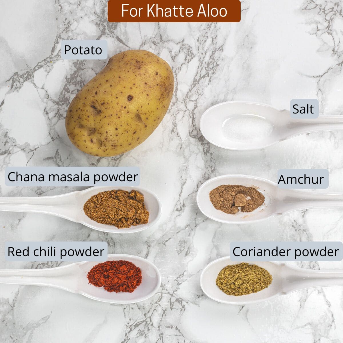 Khatte aloo ingredients in spoons with label.