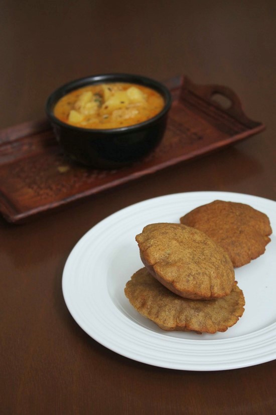 Singhare ki puri in a plate with sabzi bowl in the back in a tray.