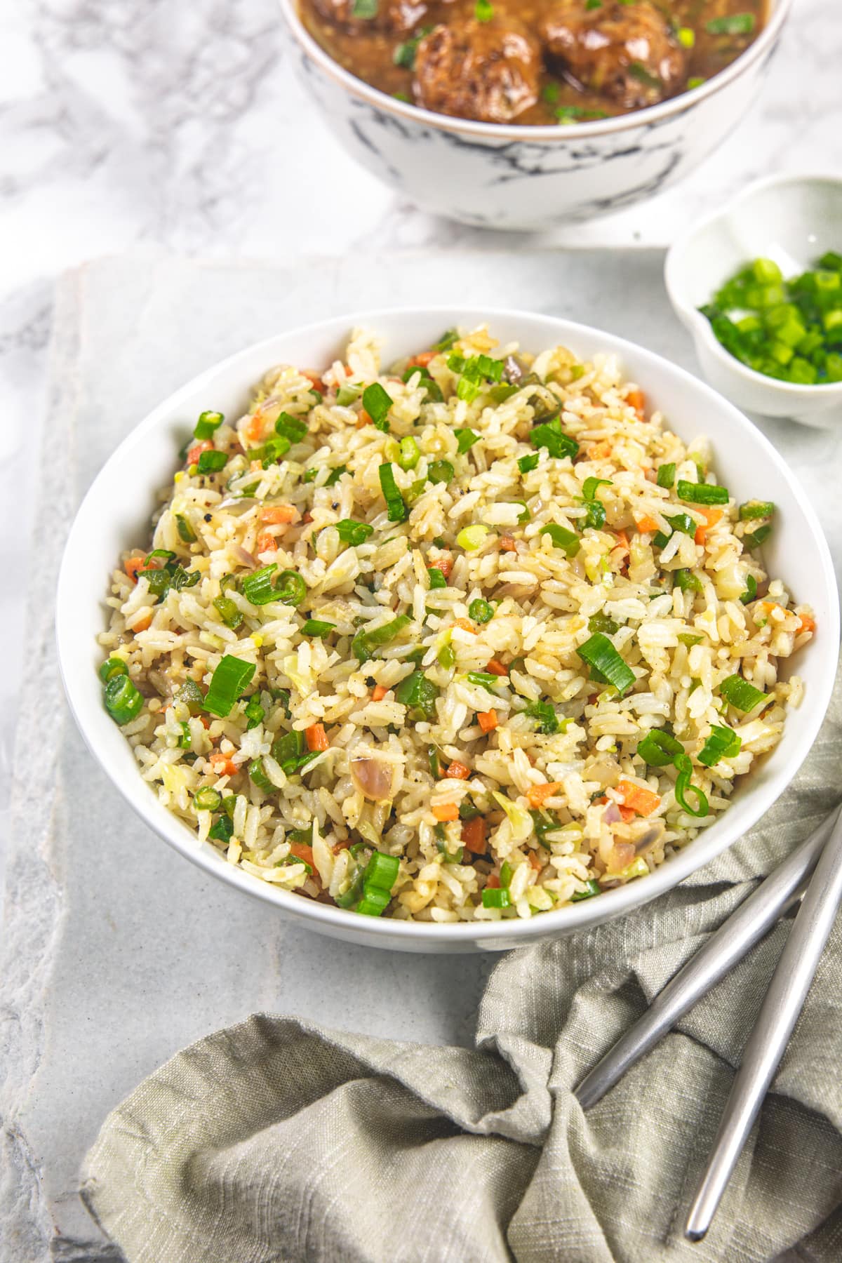 A bowl of veg fried rice with napkin, forks on the side.