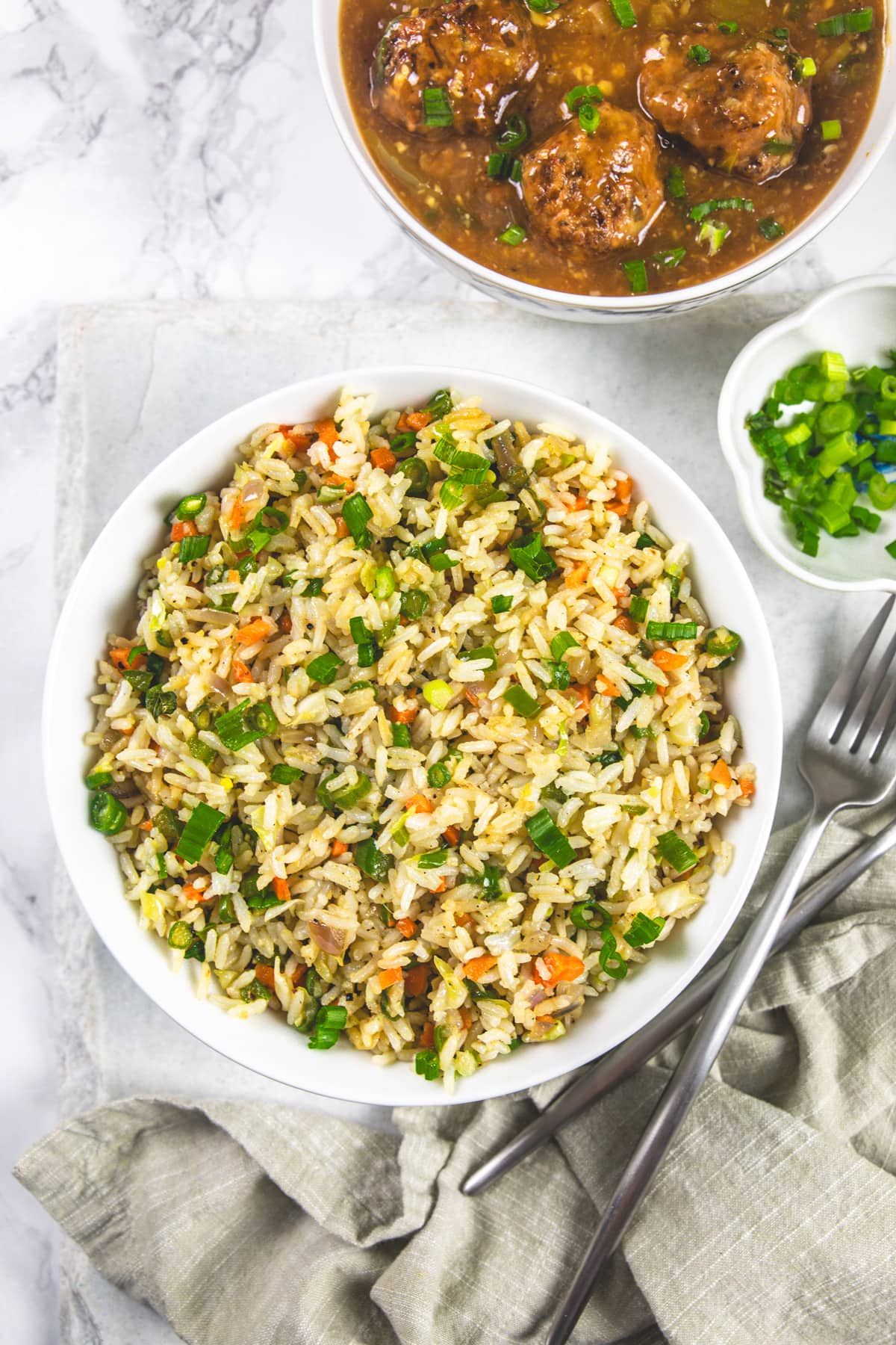 Indian Veg fried rice served with manchurian, extra spring onions and napkin, forks on the side.