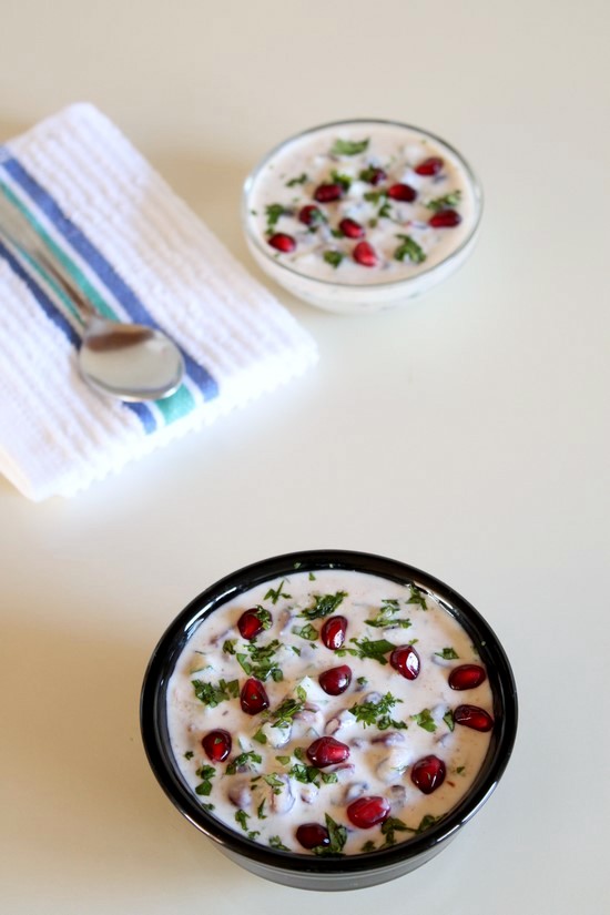 Pomegranate raita recipe - mix of sweet and savory flavors in this raita. Made with fresh pomegranate arils, cucumber, yogurt and spiced with black pepper and roasted cumin powder. Garnished with mint and cilantro leaves. This Indian raita is served with spicy curry or rice, biryani #raita #Indianfood